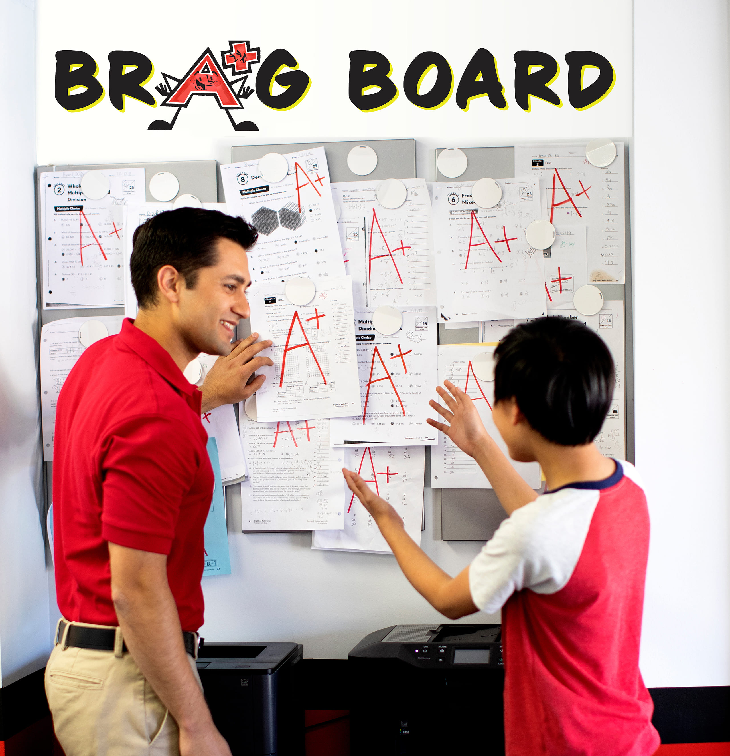Student and math tutor next to achievement board.