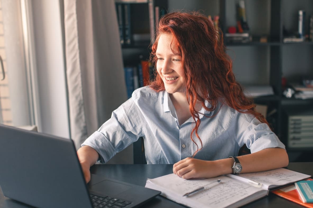 A student in a virtual math class, smiling as she learns new concepts with her tutor.