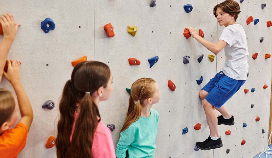 Kids looking at a climbing mountain as boy is climbing up the mountain