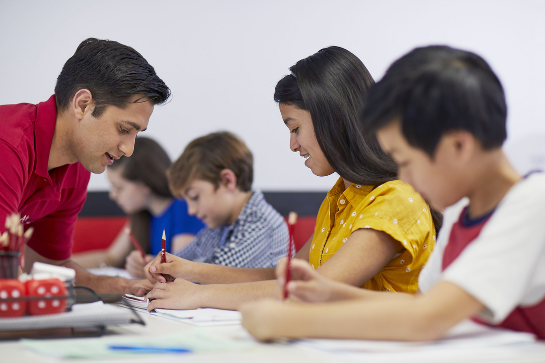 Instructor providing personalized math support to a group of engaged students in a learning center setting