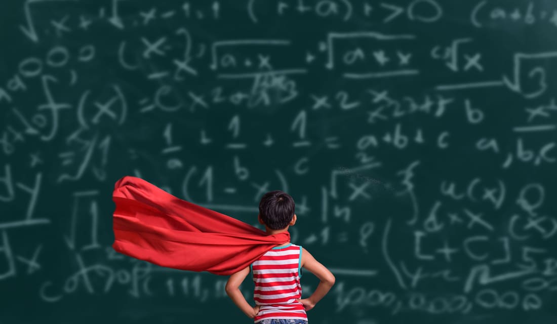 Young boy wearing a red cape standing confidently in front of a chalkboard filled with complex math equations, symbolizing a growth mindset and confidence in learning math