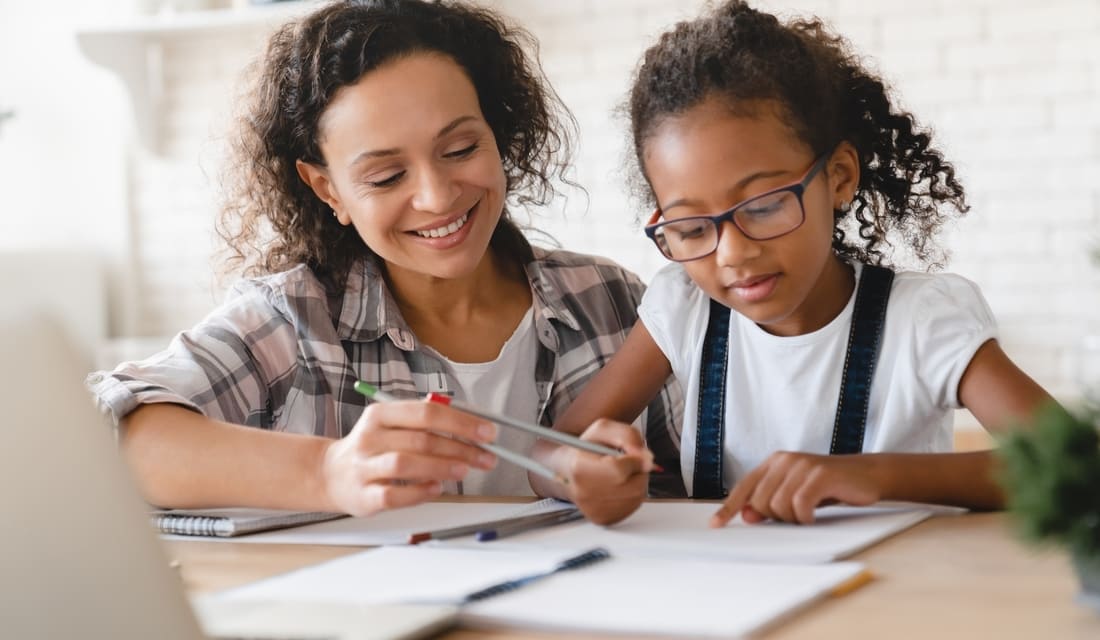 A woman and a child collaborate on a project, focused on their work together at a table.