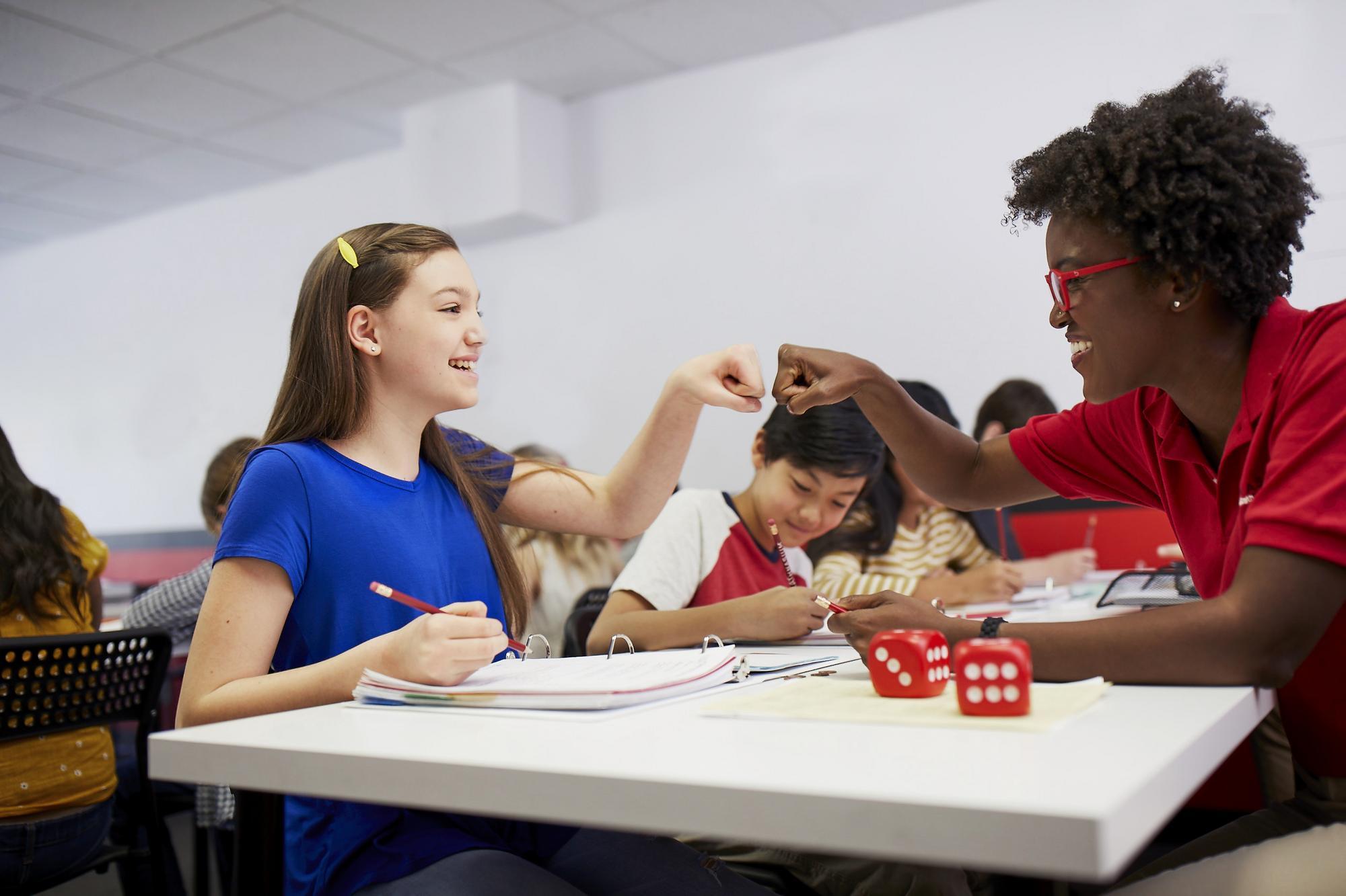 Mathnasium tutor and student fist bump after successfully solving a math problem