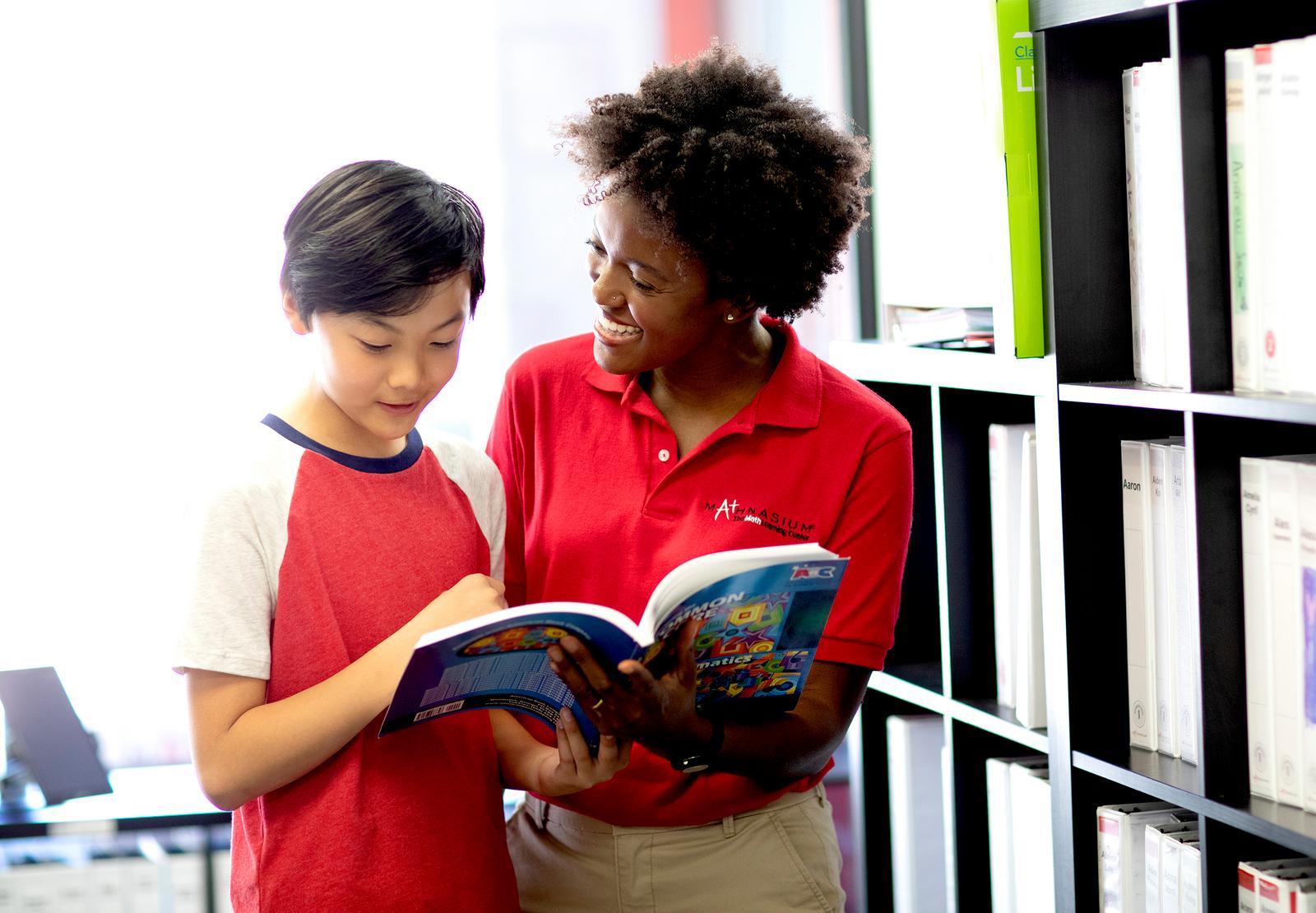Mathnasium tutor and student flip through a math textbook to understand a concept.