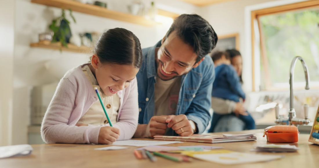 A father and daughter collaborate on a project, focused and engaged in their work together at a table.