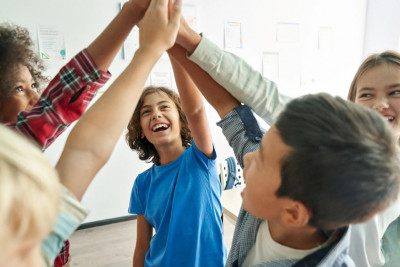 A diverse group of children, hands joined together, symbolizing friendship and cooperation in a playful setting.