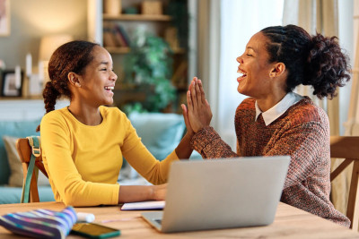 A mother and daughter are seated at a table, their hands intertwined, reflecting a bond of affection and support.