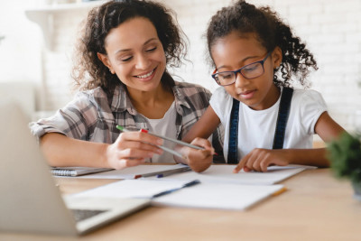 A mother and daughter collaborating on homework at a table, focused and engaged in their work together.
